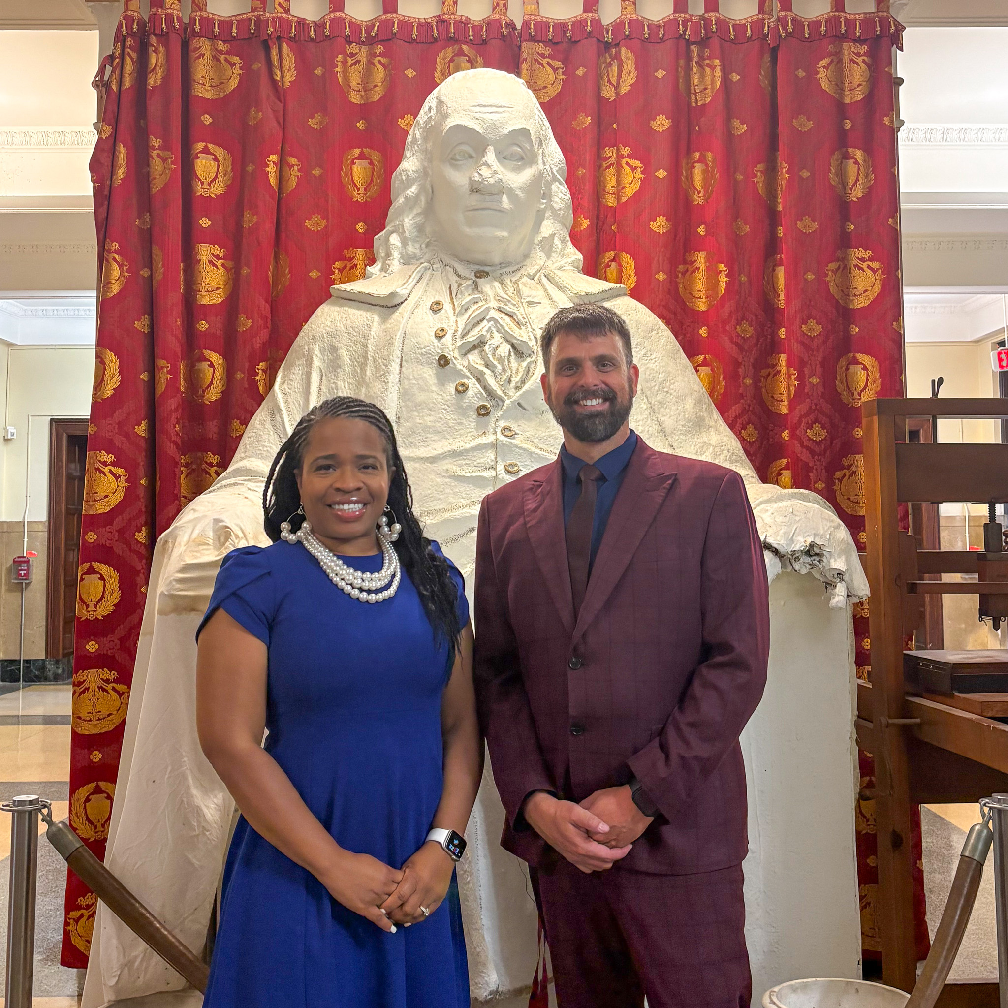 Assistant Principal Roshanna Floyd and Principal Dr. Ryan Sullivan stand in front of a statue of Benjamin Franklin.