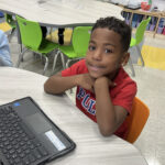 Benjamin Franklin School student seated at a classroom table with a laptop.